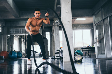Naklejka na ściany i meble Men with battle rope in functional training fitness gym
