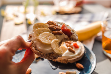eating a delicious toast on a blue plate. hand holding toast. breakfast at home. cup of tea with lemon and banana and almond toast. breakfast at home. breakfast idea. simple breakfast decoration
