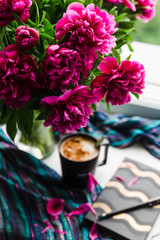 working at home idea. big peonies bouquet and a cup of coffee. spring at home. home decor and relaxation. coffee break and beautiful flowers, workplace at home, working at home