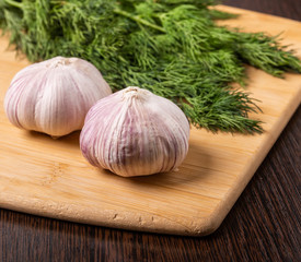 Garlic and dill are on the cutting Board.