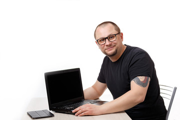 A man sits at a table with glasses and works on a laptop. On a white background.
