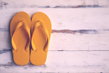 Pair of yellow slippers on wood background.