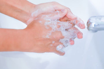 Naklejka premium Close-up of young women washing hands with soap rubbing fingers and skin under faucet water flows on white basin for pandemic prevention Coronavirus, Covid-19