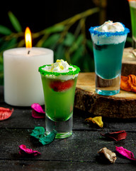 green cocktail shot with strawberry and whipped cream