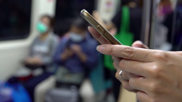 4K, Asian Woman Using Mask For Protection Of Coronavirus And Using  Smartphone On Active Subway As She Waits For Arrive Her Stop Station. Checks Social Network And Write Text Done On Phone Device.-Dan