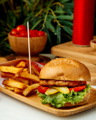hamburger with french fries on wooden board