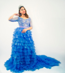 Beautiful young woman in gorgeous blue long dress like Cinderella with perfect make-up and hair style. Copy space