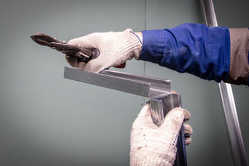 Worker cuts a metal profile for the walls.