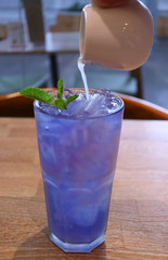 Pitcher of Fresh Lime Juice Pouring into Iced Butterfly Pea Flower Tea