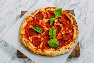 Italian pizza with mozzarella cheese and basil on a marble table