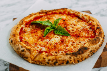 Italian pizza with mozzarella cheese and basil on a marble table