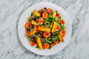 salad with salmon, caviar, eggs and vegetables on a marble table
