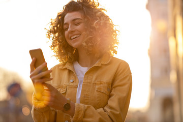 Young hipster woman using smartphone at sunset
