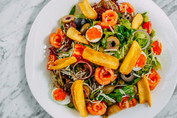 salad with salmon, caviar, eggs and vegetables on a marble table