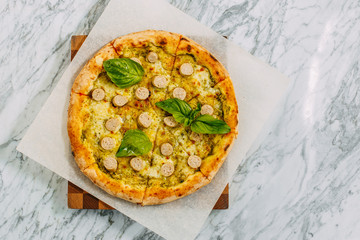 Italian pizza with mozzarella cheese and basil on a marble table