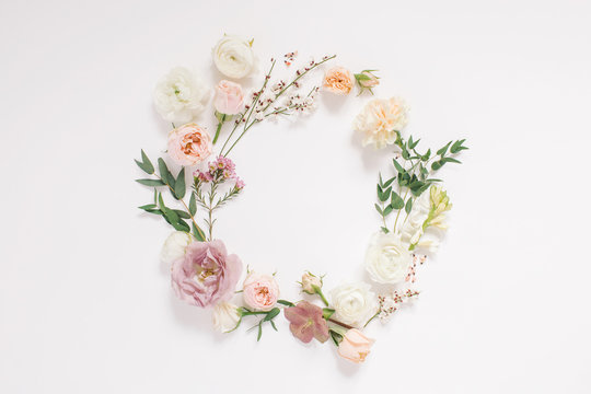 Round frame wreath pattern with fresh flower buds, branches and leaves isolated on white background. flat lay, top view.