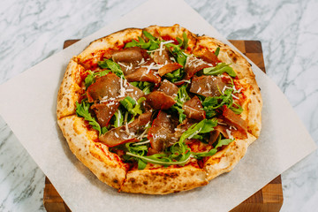 Italian pizza with mozzarella cheese and basil on a marble table