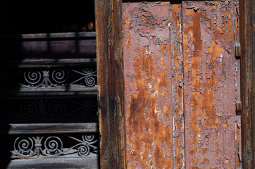 Old wooden door with peeling paint and an iron staircase