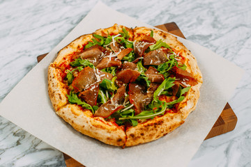 Italian pizza with mozzarella cheese and basil on a marble table