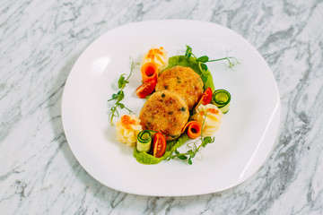 fish cakes with caviar and vegetables on a marble table
