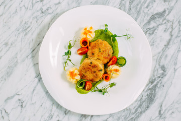 fish cakes with caviar and vegetables on a marble table