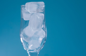 A glass of ice on a blue background.Tableware for alcohol.A glass for champagne and wine.Chilled drinks.