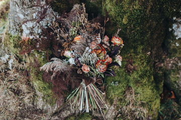 Bouquet. Bouquet of red, pink and green colors with silk ribbon lying on moss in the mountains