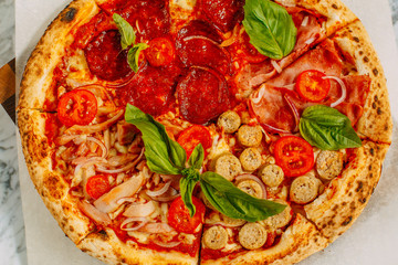 Italian pizza with mozzarella cheese and basil on a marble table