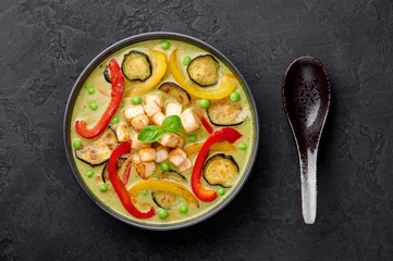 Vegetarian Thai Green Curry with tofu in black bowl at dark slate background. Veg Green Thai Curry is thailand cuisine dish with green chillies paste, basil, spices and vegetables. Thai Food