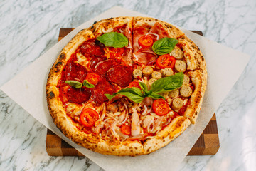 Italian pizza with mozzarella cheese and basil on a marble table
