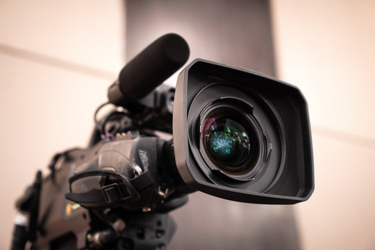 Television Camera Lens, Film Of Video Movie Recording Films Shooting Of Grand Opening In Conference Hall Live Streming For Presentation With Bokeh Light Background. Media Production Concept