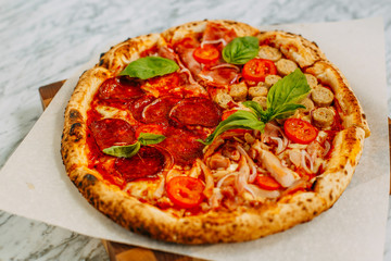 Italian pizza with mozzarella cheese and basil on a marble table