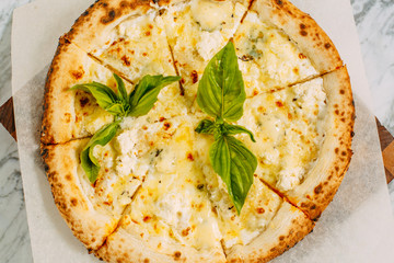 Italian pizza with mozzarella cheese and basil on a marble table