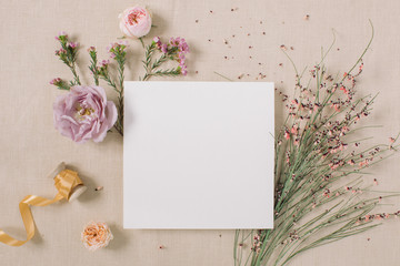 Empty white paper blank, flower buds, branches on beige background. Wedding branding mock up,  holiday marketing concept.