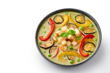 Vegetarian Thai Green Curry with tofu in black bowl isolated on white background. Veg Green Thai Curry is thailand cuisine dish with green chillies paste, basil, spices and vegetables. Isolate