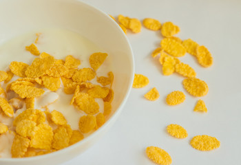 Cornflakes with milk in a deep white bowl. White background. Delicious and healthy Breakfast.