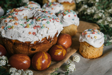 Easter cake and colored eggs on the background of blooming flowers