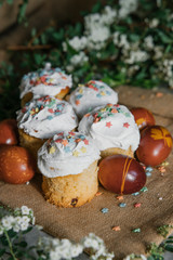 Easter cake and colored eggs on the background of blooming flowers