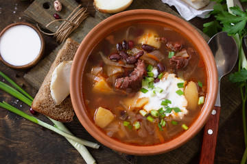 The concept of healthy and diet food. Russian or Ukrainian cuisine. Soup with meat and beans or Borsch served with sour cream on a rustic wooden table.