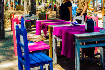 Fototapeta na wymiar National Turkish style in the interior of an open-air restaurant. Colored chairs, tables and textiles. Summer. Pine forest.