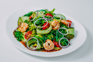 fresh vegetable salad with shrimp, with lemon and wine on a white background