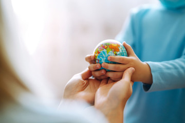 Child in protective sterile medical mask with mother holding a world globe. Save planet. The concept of preventing the spread of the epidemic coronavirus.