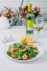 fresh vegetable salad with shrimp, with lemon and wine on a white background