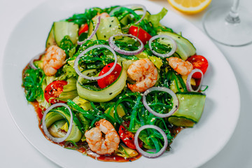 fresh vegetable salad with shrimp, with lemon and wine on a white background