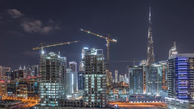 Skyline of the city at night with beautiful canal with reflections and bright skyscrapers aerial timelapse in Business Bay, Dubai, United Arab Emirates. Towers under construction