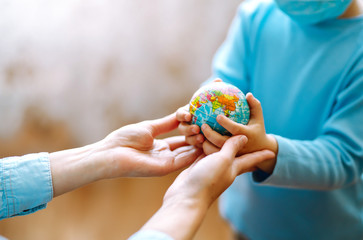 Child in protective sterile medical mask with mother holding a world globe. Save planet. The concept of preventing the spread of the epidemic coronavirus.