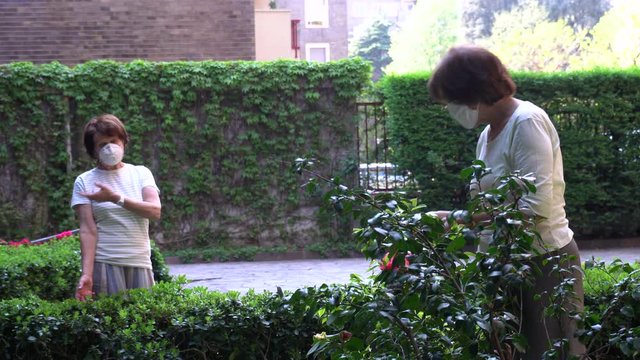 Europe, Italy, Milan, elderly 70-year old ladies with mask speak in the courtyard  building where live keeping the safety distance of one meter,  stay at home during n-cov19 CORONAVIRUS epidemic adult