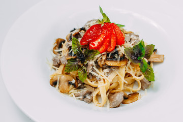 Italian pasta in a creamy sauce with mushrooms champignon on a white plate