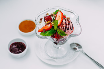 three balls of ice cream with syrup and fruit on a white background