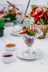 three balls of ice cream with syrup and fruit on a white background